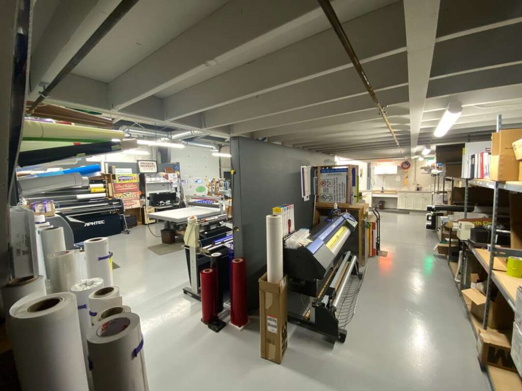 Print shop with rolls of material and large-format printers.