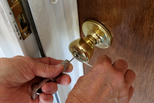 Locksmith repairing a door lock with tools.